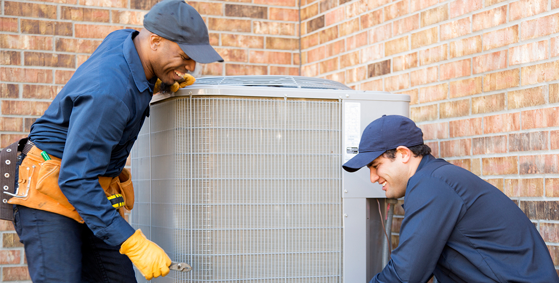Two technicians working on an HVAC unit